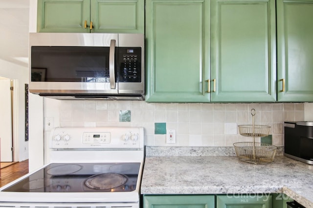 kitchen featuring light stone counters, white range with electric cooktop, green cabinets, and backsplash