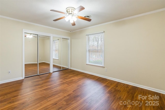 unfurnished bedroom featuring dark hardwood / wood-style flooring, multiple closets, crown molding, and ceiling fan