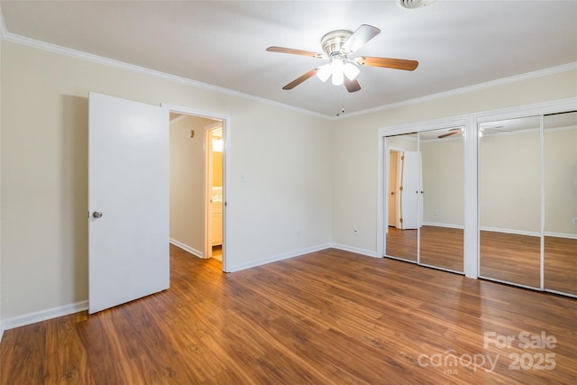 unfurnished bedroom with crown molding, wood-type flooring, ceiling fan, and two closets