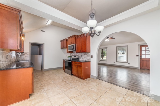 kitchen featuring sink, appliances with stainless steel finishes, tasteful backsplash, light tile patterned flooring, and dark stone counters