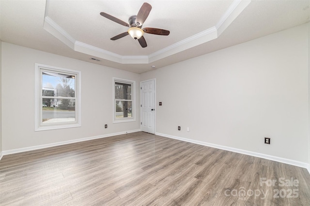 unfurnished room with a raised ceiling, crown molding, ceiling fan, and light hardwood / wood-style floors