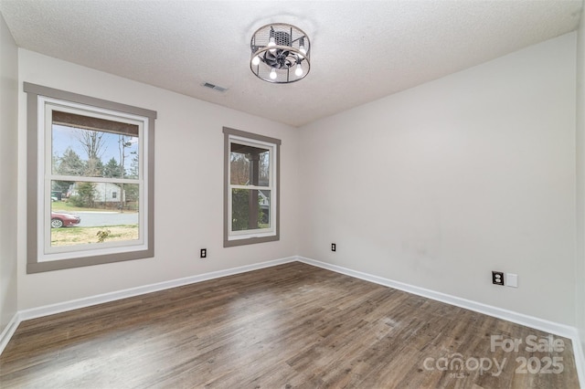 spare room with a notable chandelier, dark wood-type flooring, and a textured ceiling