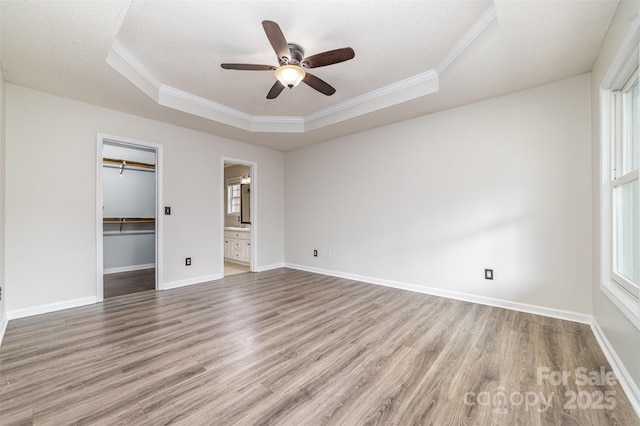 unfurnished bedroom with wood-type flooring, ornamental molding, a textured ceiling, and a tray ceiling