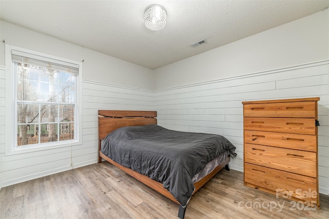 bedroom with a textured ceiling and light wood-type flooring