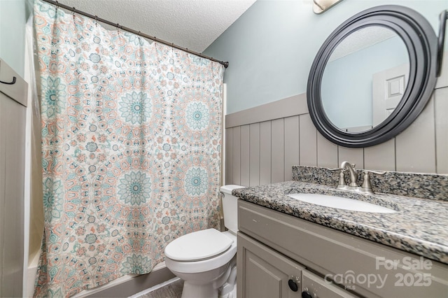 bathroom with vanity, curtained shower, toilet, and a textured ceiling