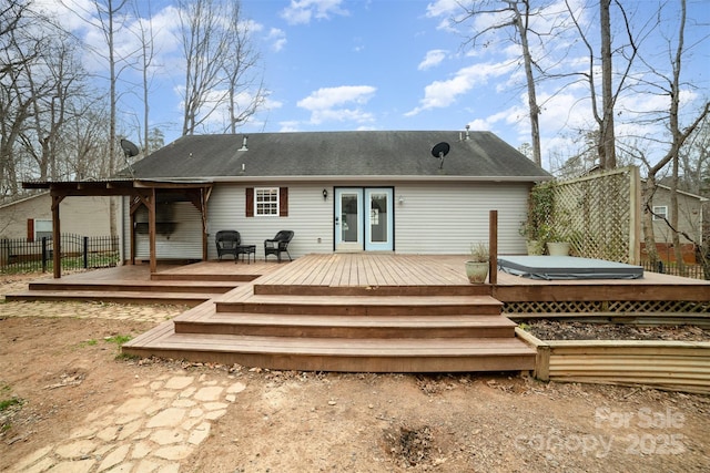 rear view of house with a covered hot tub and a deck