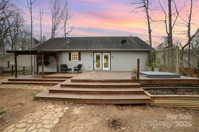 back house at dusk with a covered hot tub and a deck