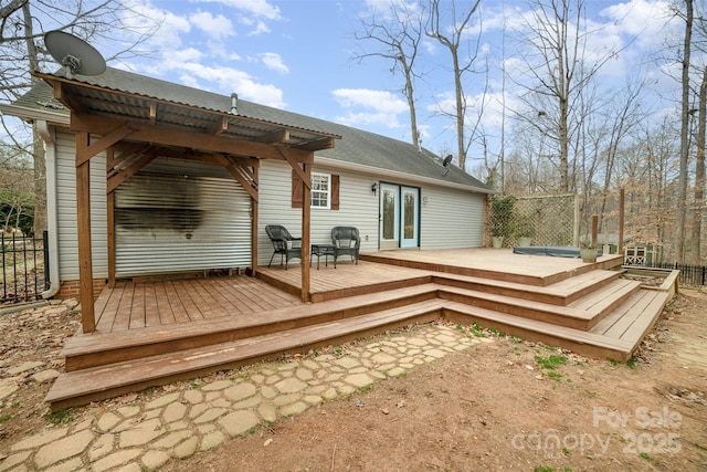 rear view of house with a hot tub and a wooden deck