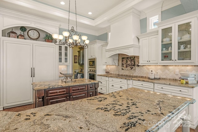 kitchen featuring appliances with stainless steel finishes, decorative light fixtures, white cabinetry, and custom exhaust hood