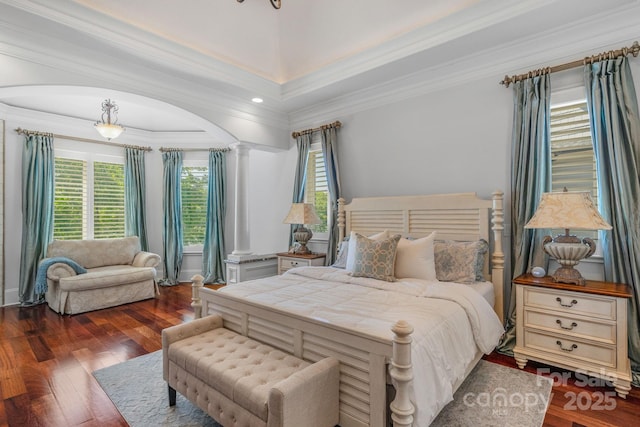 bedroom featuring dark hardwood / wood-style floors, ornamental molding, and decorative columns