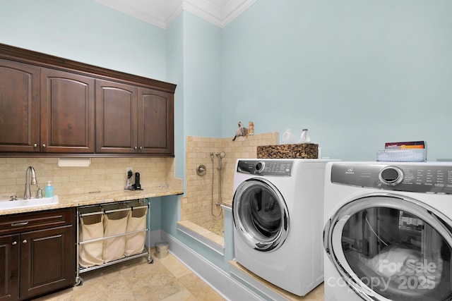 clothes washing area featuring cabinets, ornamental molding, sink, light tile patterned floors, and washing machine and dryer