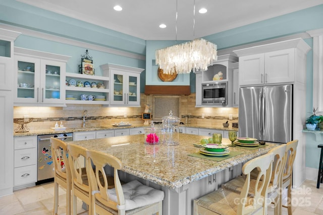 kitchen with decorative light fixtures, a kitchen island, white cabinetry, and stainless steel appliances