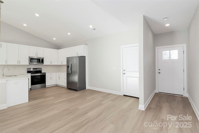 kitchen with sink, light hardwood / wood-style flooring, white cabinets, and appliances with stainless steel finishes