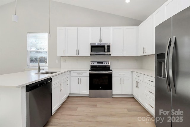 kitchen with sink, stainless steel appliances, white cabinets, decorative light fixtures, and kitchen peninsula