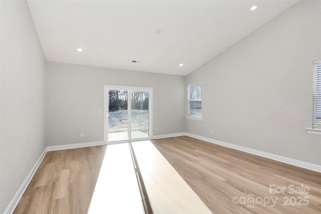 unfurnished room featuring lofted ceiling and light wood-type flooring