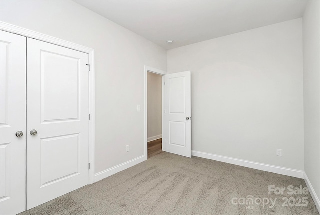 unfurnished bedroom with light colored carpet and a closet