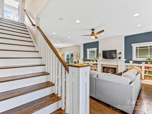 living room with dark hardwood / wood-style floors, ceiling fan, and a high end fireplace