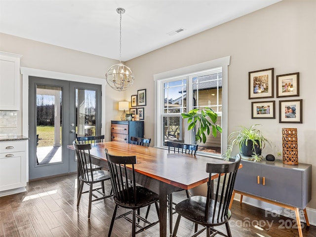 dining area with plenty of natural light, french doors, dark wood-type flooring, and a chandelier