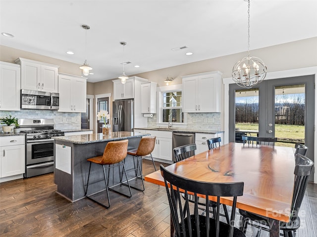 kitchen featuring pendant lighting, a center island, white cabinets, and stainless steel appliances