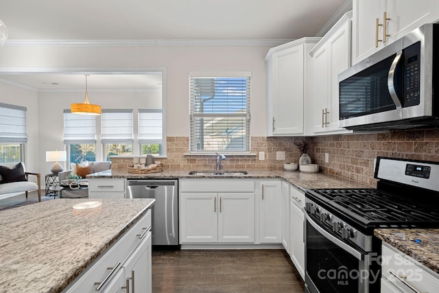 kitchen featuring appliances with stainless steel finishes, light stone counters, white cabinets, backsplash, and sink