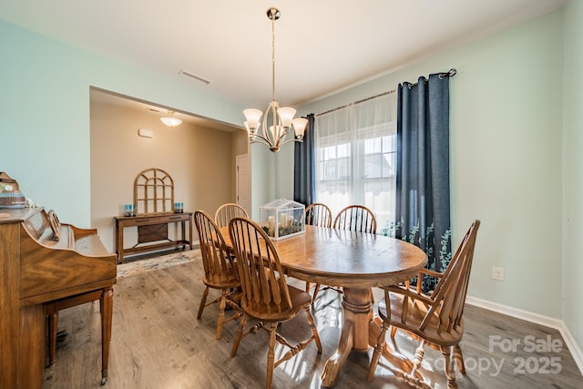 dining area with wood-type flooring and an inviting chandelier