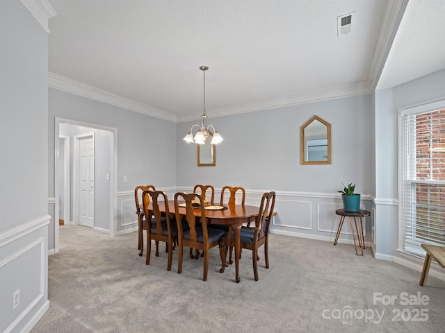 carpeted dining space featuring ornamental molding and a notable chandelier