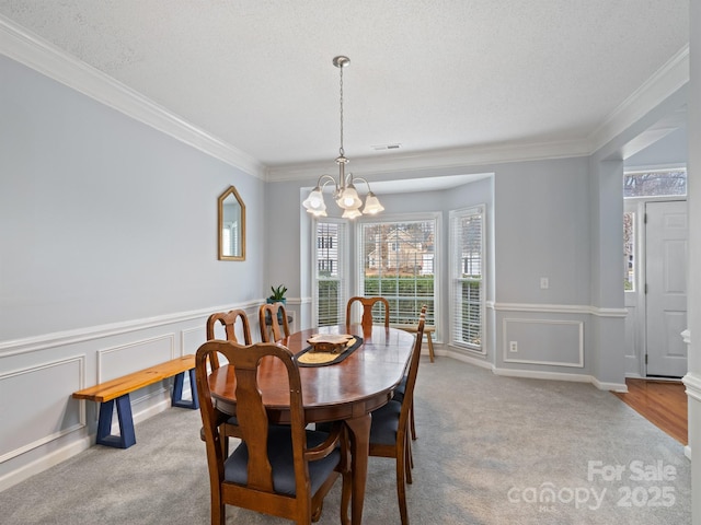 dining space with ornamental molding, light carpet, a textured ceiling, and an inviting chandelier