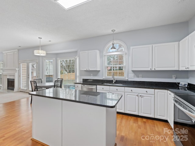 kitchen featuring sink, hanging light fixtures, stainless steel appliances, a center island, and white cabinets