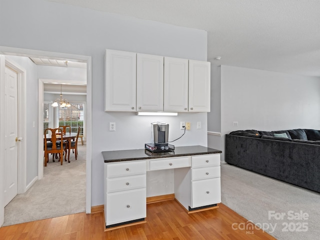 home office with light hardwood / wood-style flooring and a notable chandelier