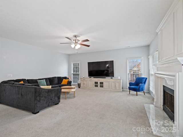 living room featuring ceiling fan, a high end fireplace, and light carpet