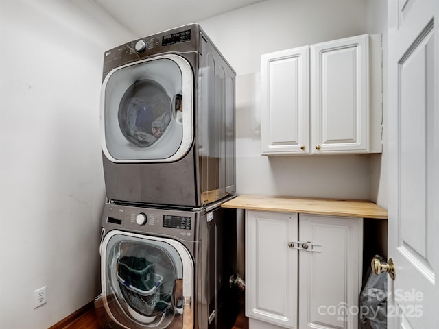 laundry room featuring cabinets and stacked washer / dryer