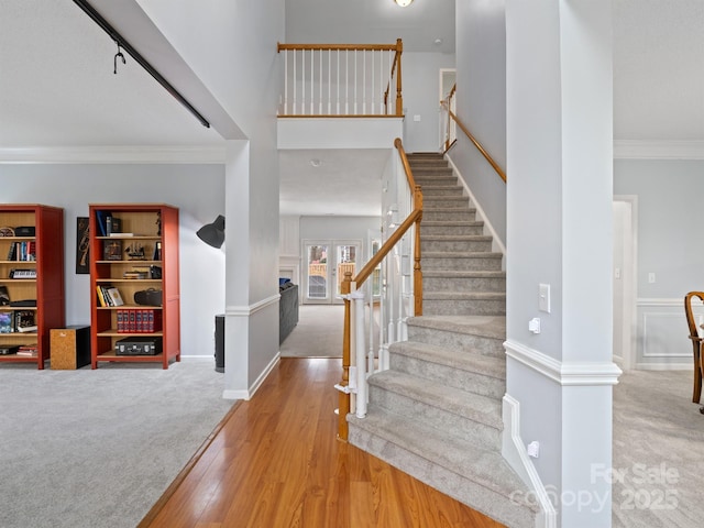 foyer featuring crown molding, carpet flooring, and a towering ceiling