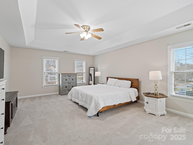 carpeted bedroom featuring ceiling fan and a tray ceiling