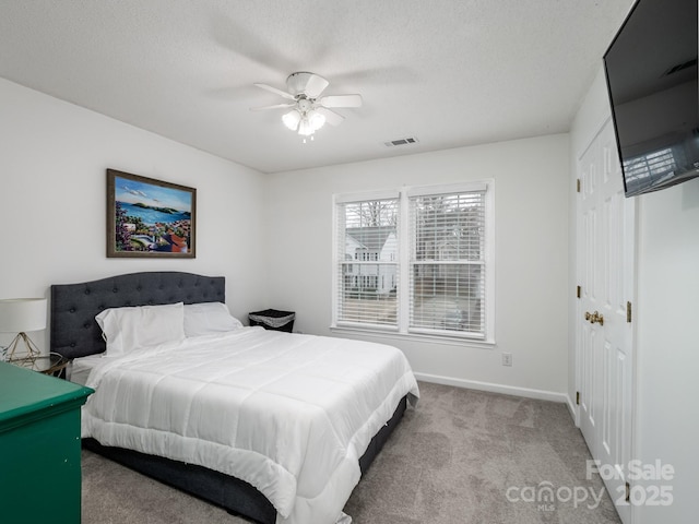 carpeted bedroom with ceiling fan, a closet, and a textured ceiling