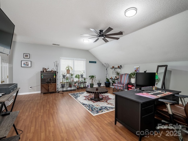 home office with lofted ceiling, hardwood / wood-style flooring, a textured ceiling, and ceiling fan