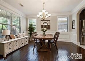 dining space featuring dark wood-type flooring, a notable chandelier, and ornamental molding