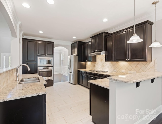 kitchen with a kitchen breakfast bar, sink, hanging light fixtures, crown molding, and stainless steel appliances