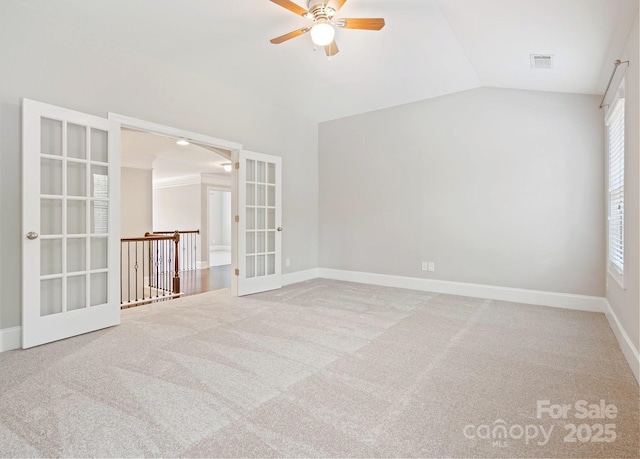 carpeted spare room featuring ceiling fan, french doors, a healthy amount of sunlight, and vaulted ceiling