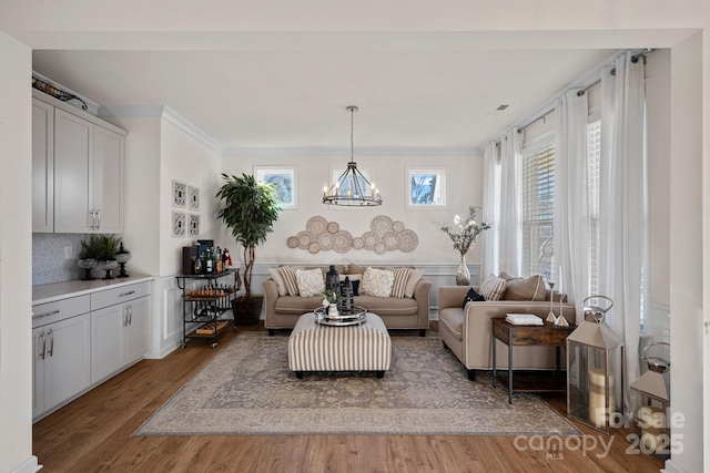 living room with crown molding, a chandelier, and hardwood / wood-style floors