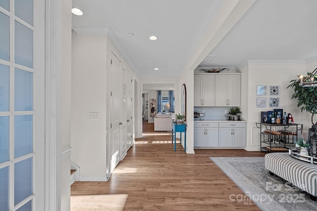 hall with crown molding and light hardwood / wood-style flooring