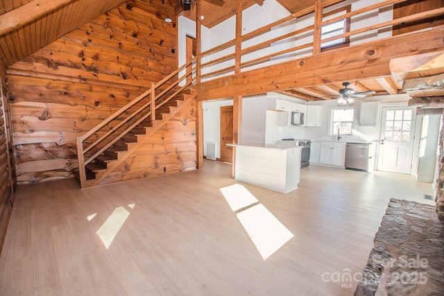 unfurnished living room featuring high vaulted ceiling, wooden walls, ceiling fan, light hardwood / wood-style floors, and wood ceiling