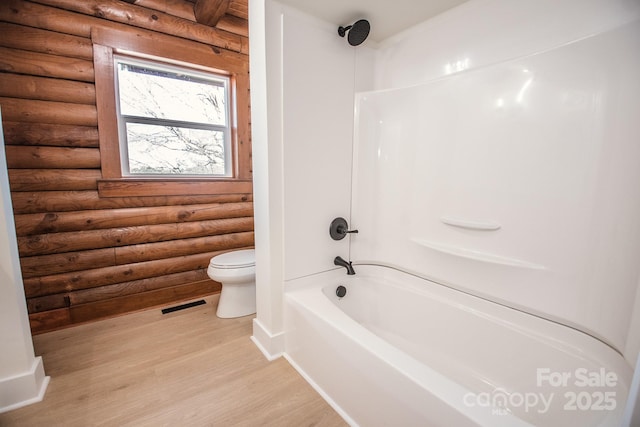 bathroom featuring log walls, shower / bath combination, toilet, and hardwood / wood-style flooring