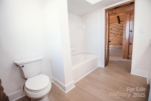 bathroom with hardwood / wood-style floors, bathtub / shower combination, and toilet