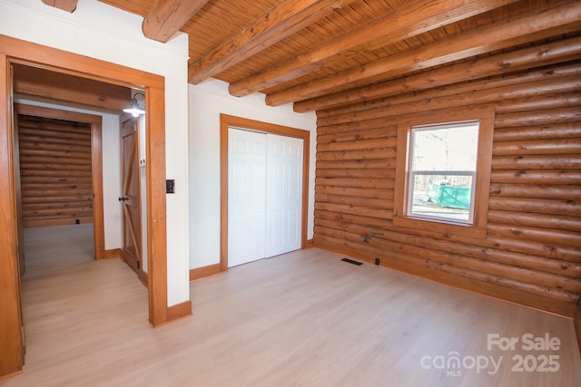 unfurnished bedroom featuring beam ceiling, rustic walls, wooden ceiling, light hardwood / wood-style floors, and a closet