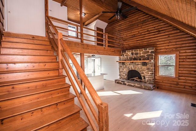 stairs featuring high vaulted ceiling, a stone fireplace, rustic walls, beam ceiling, and wood ceiling