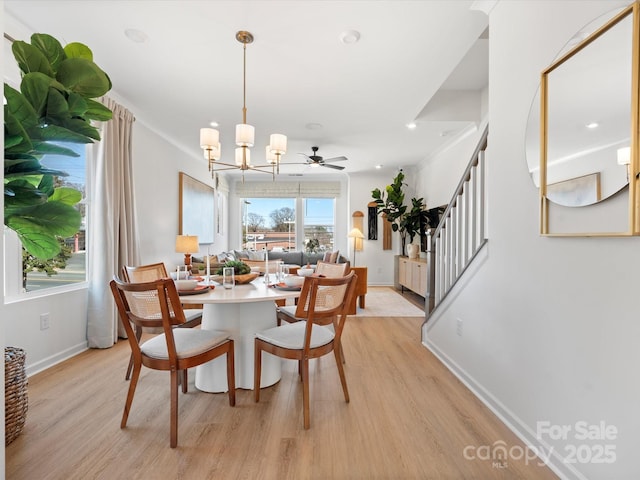 dining space featuring light wood-style floors, baseboards, an inviting chandelier, and stairs