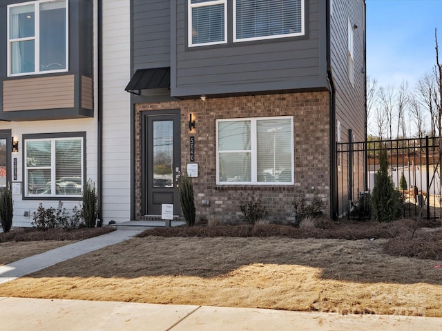 doorway to property with fence and brick siding