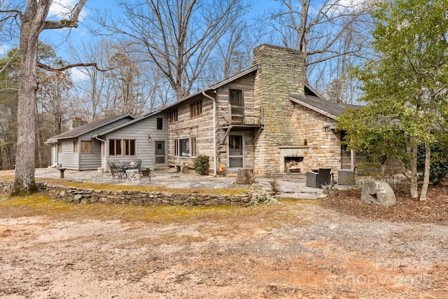 back of property with a patio and an outdoor stone fireplace