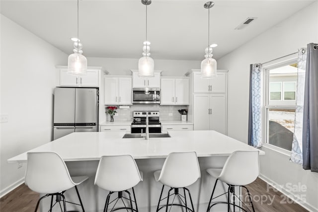 kitchen featuring stainless steel appliances, white cabinets, backsplash, and pendant lighting