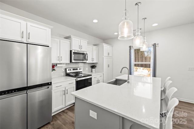 kitchen featuring sink, white cabinets, decorative light fixtures, and appliances with stainless steel finishes